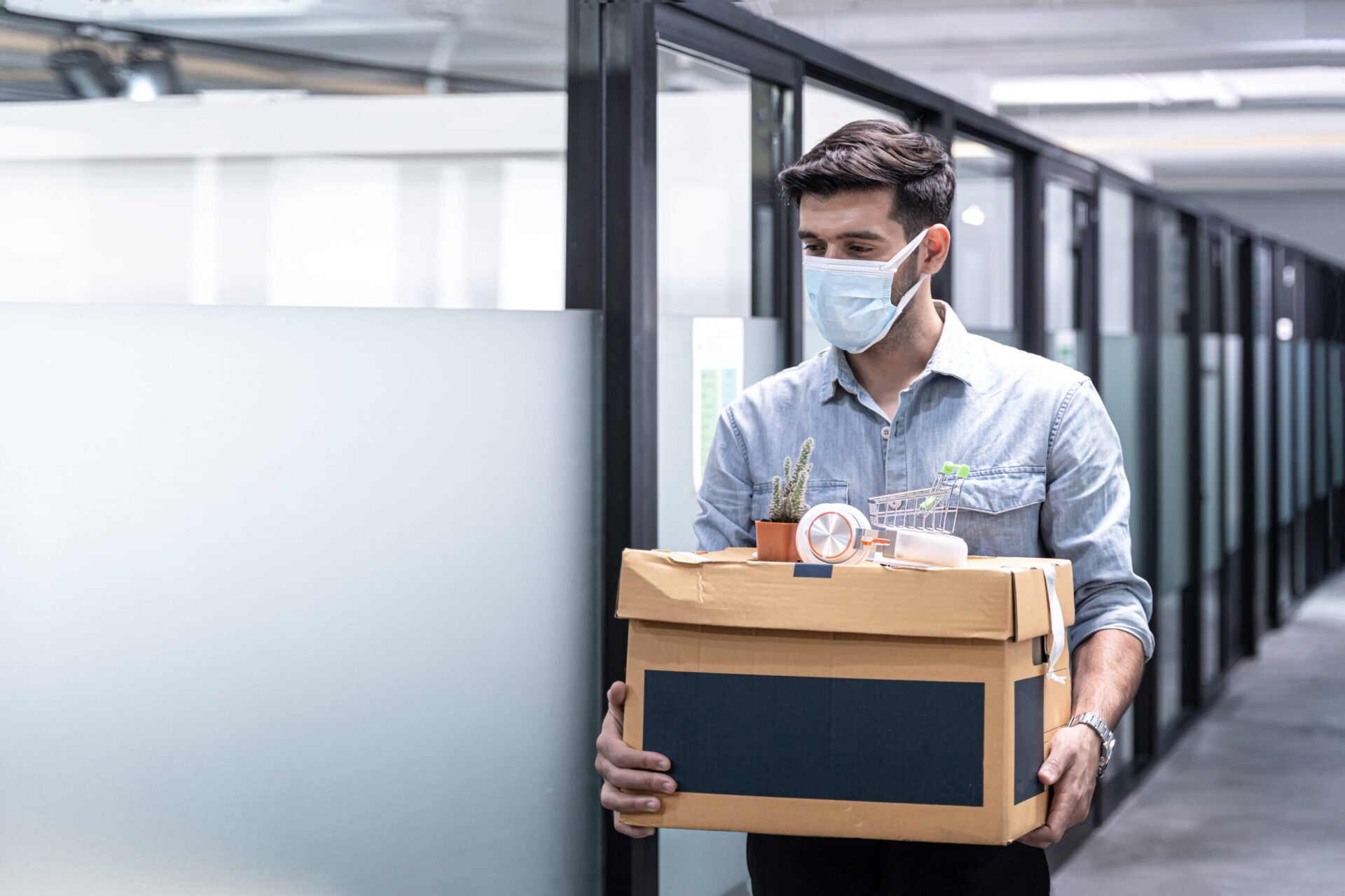 Mann mit Maske packt sachen in büro